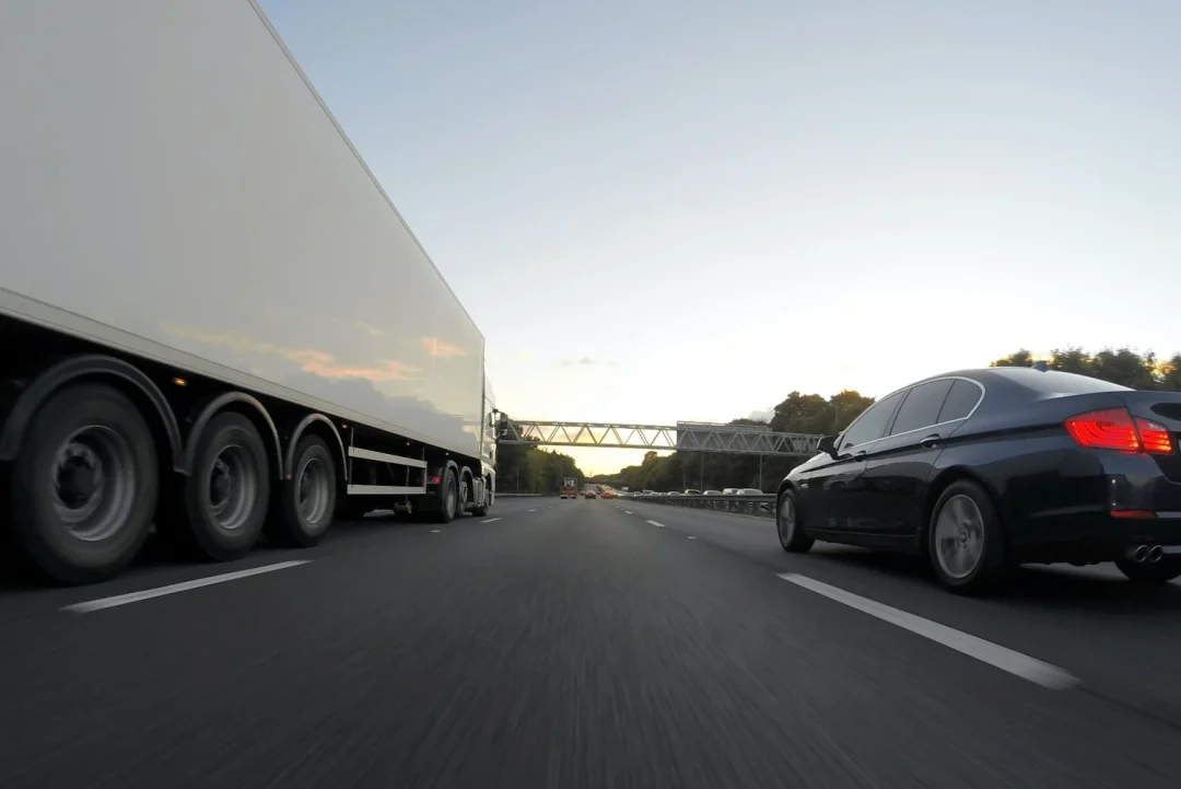 Un camion et une voiture roulent sur une voie rapide.